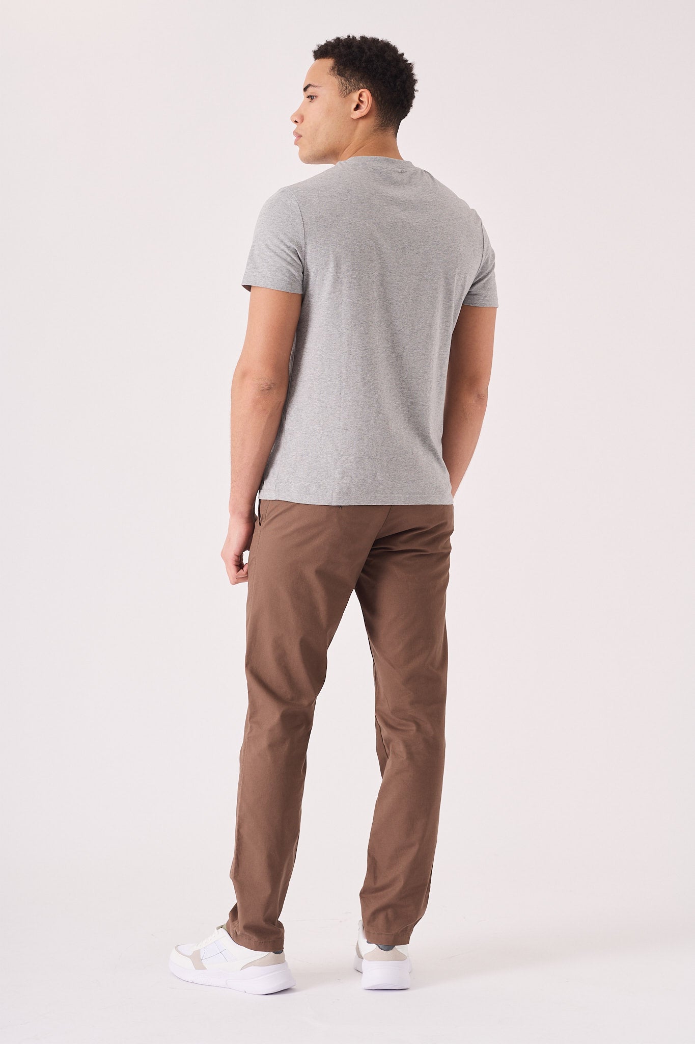Back view showing the tailored fit of the brown chino trousers.