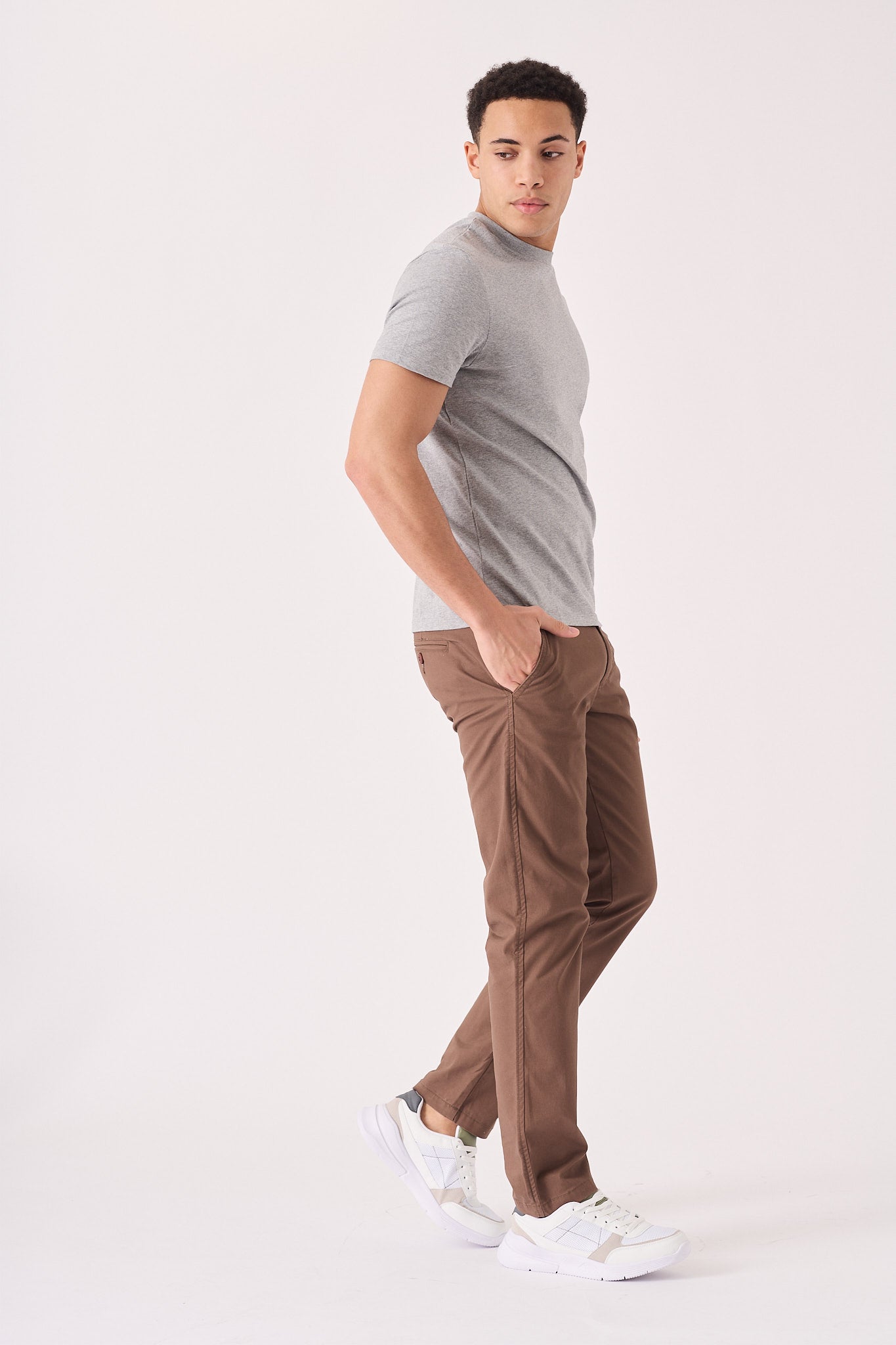 A man walking in stylish brown chino trousers for a modern look.