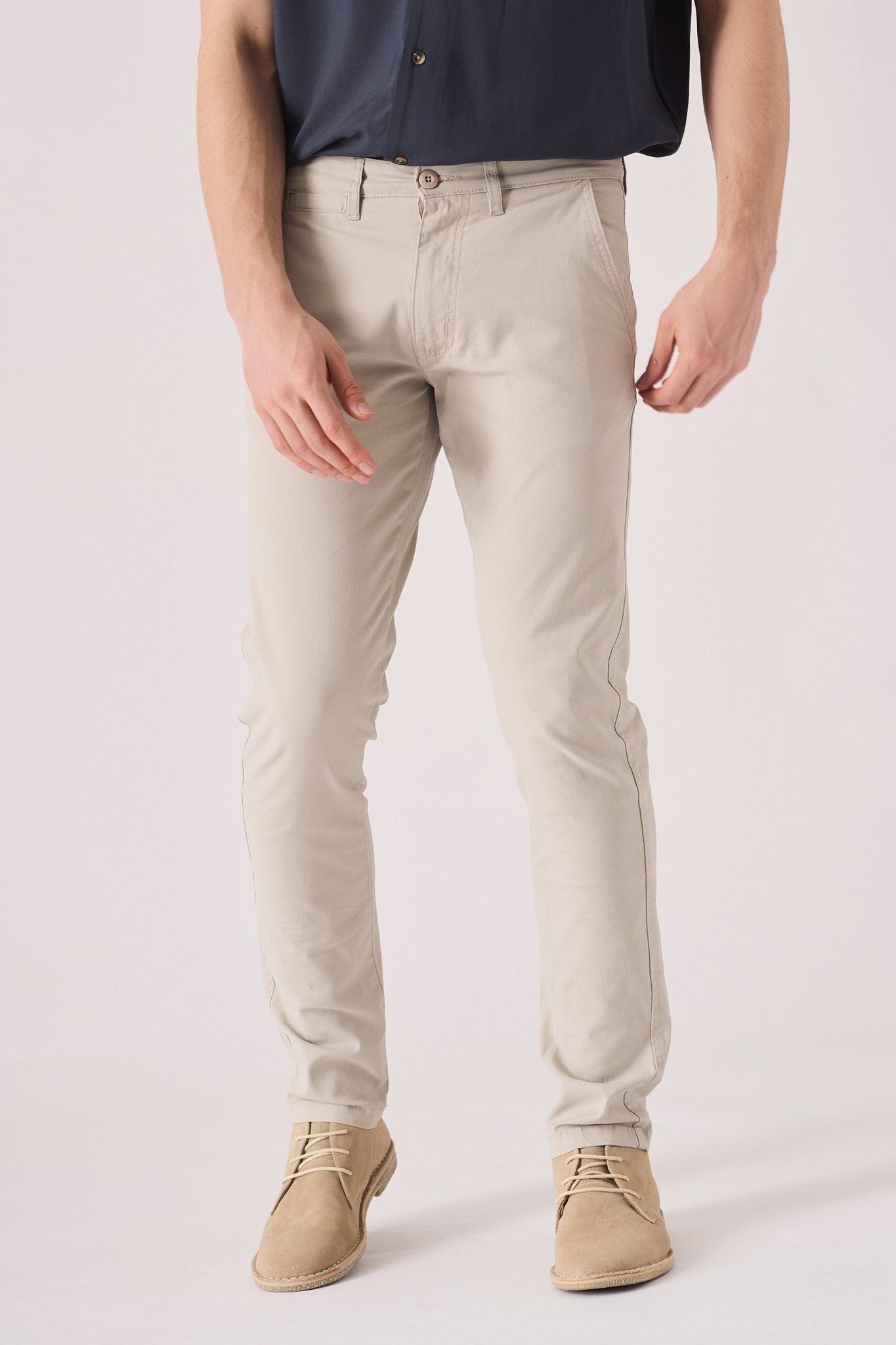 Close up of the front waist and pockets on cream chinos slim fit.