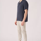 Side view of a man wearing cream chinos slim fit in a studio setting.