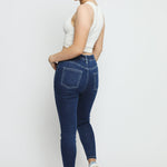 Rear view of a woman wearing slim fit dark blue denim jeggings showing the pocket detail and stretch fabric.