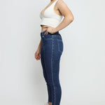 Side view of a woman wearing high-waisted dark blue denim jeggings to show the slim silhouette.