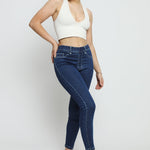 A woman posing in dark blue denim jeggings for women featuring a comfortable high-waist design and elasticated waistband.