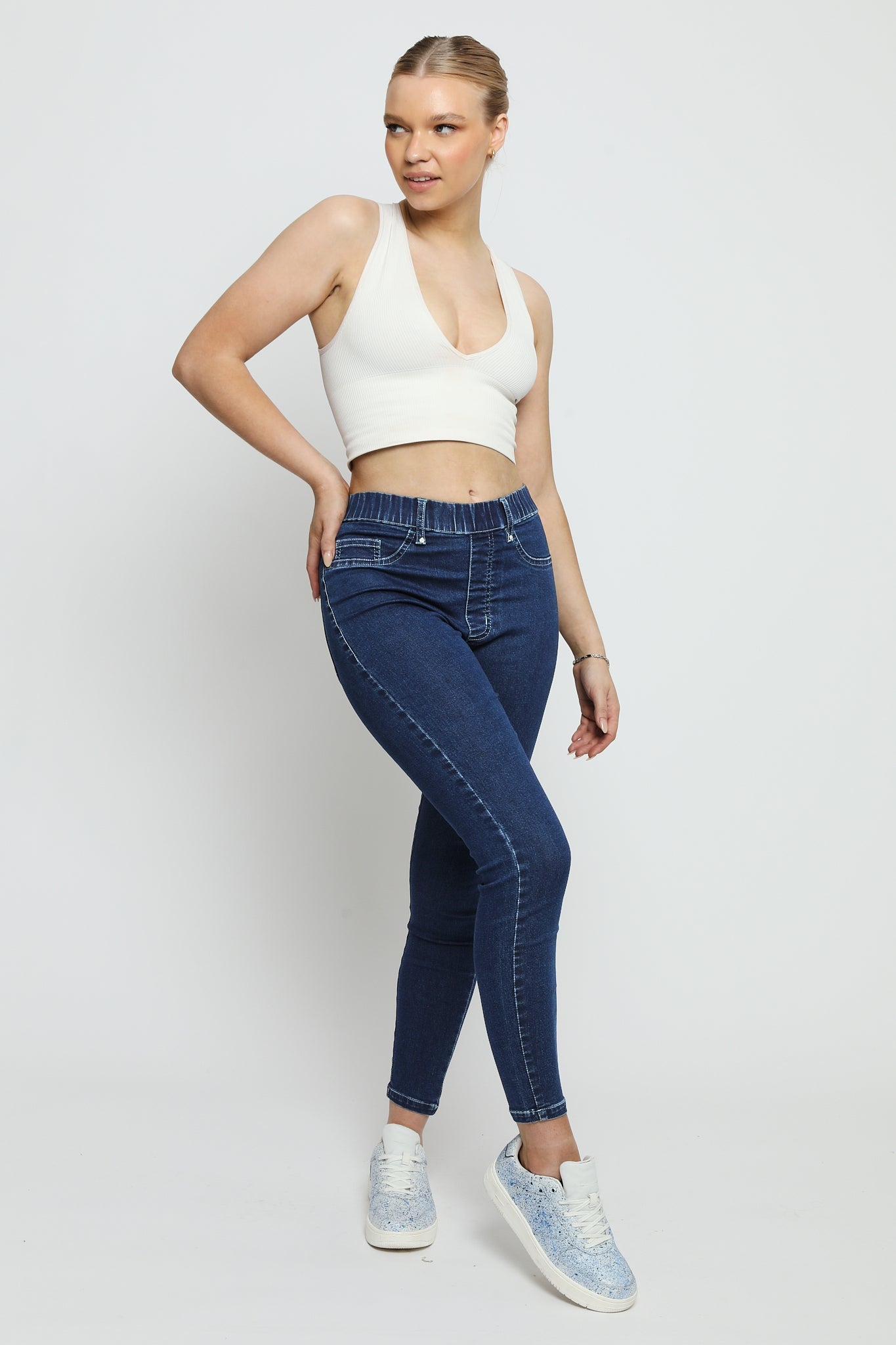 A woman posing in dark blue denim jeggings for women featuring a comfortable high-waist design and elasticated waistband.