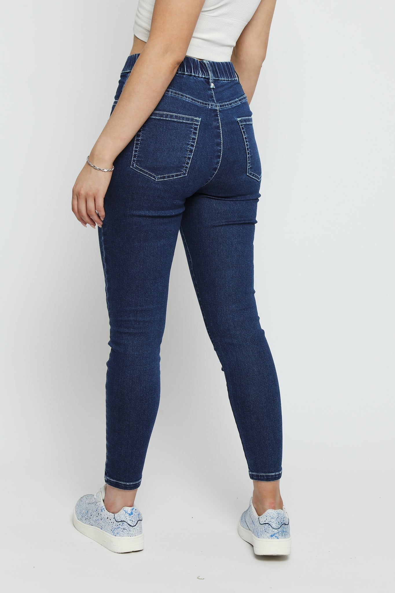Close up shot of the back of the dark blue denim jeggings for women showing the elasticated waistband and pocket design.