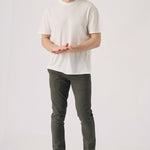 A man standing wearing dark olive green chinos in a full front view.