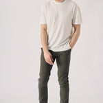 Male model walking while wearing stylish dark olive green chinos.