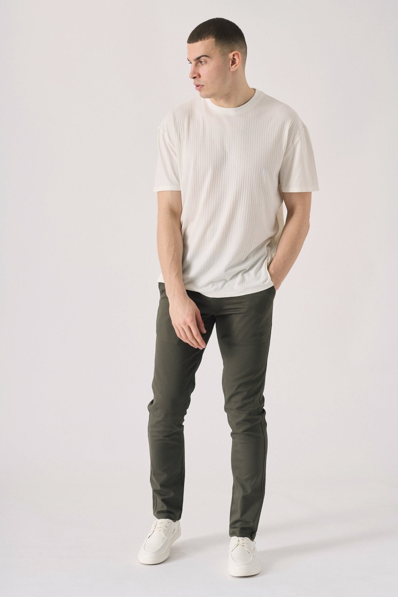 Male model walking while wearing stylish dark olive green chinos.