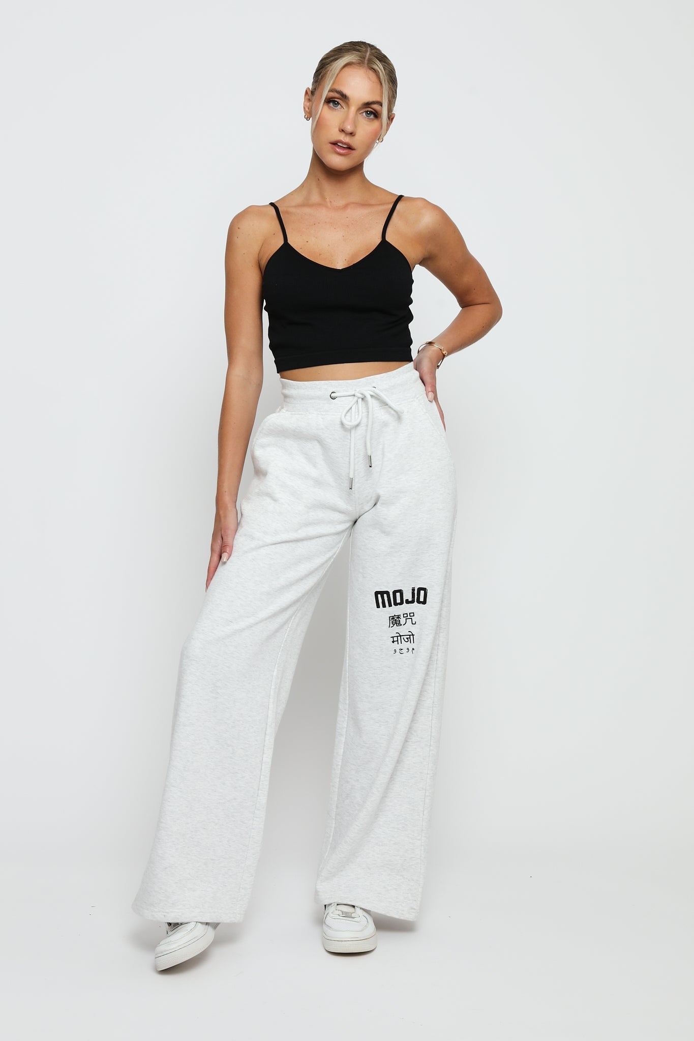 A woman standing in stylish grey marl joggers womens with a black crop top.