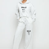 Full length view of a model in a grey marl hoodie women's and matching joggers.