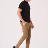 Side view of a man walking while wearing stylish light brown chinos men.