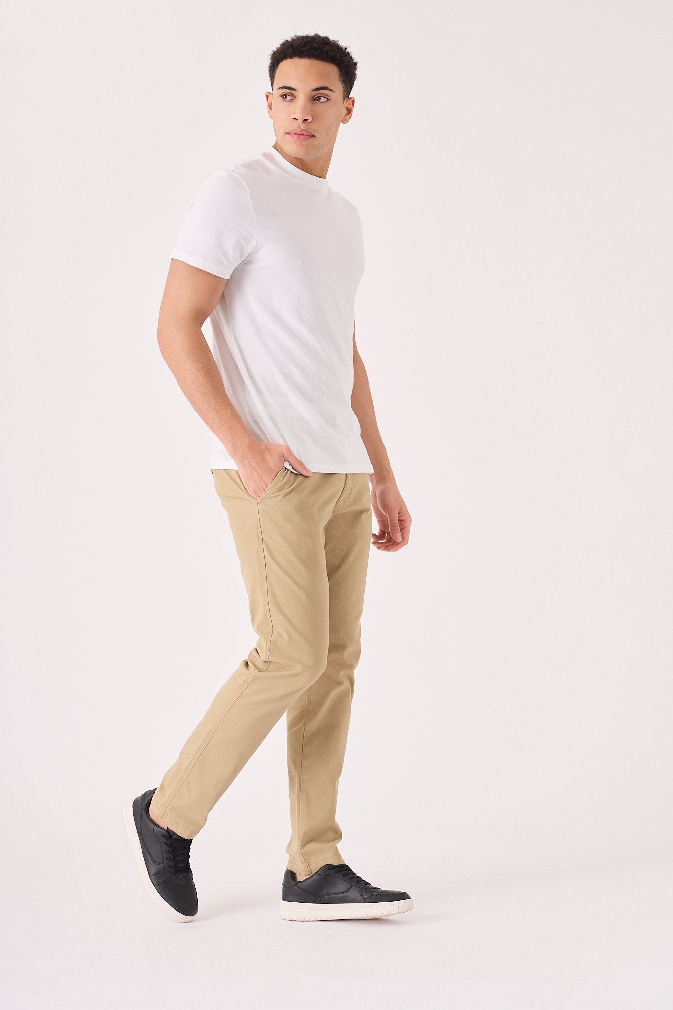 A man walking in stylish men's beige chinos slim fit with a white t-shirt.