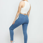 Rear view of a woman posing in slim fit mid blue denim jeggings to show the flexible stretch fabric.