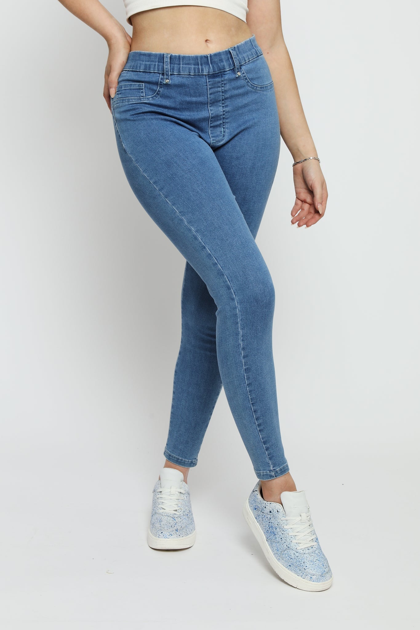 Close up of the skinny fit and fabric texture of the mid blue denim jeggings for women.