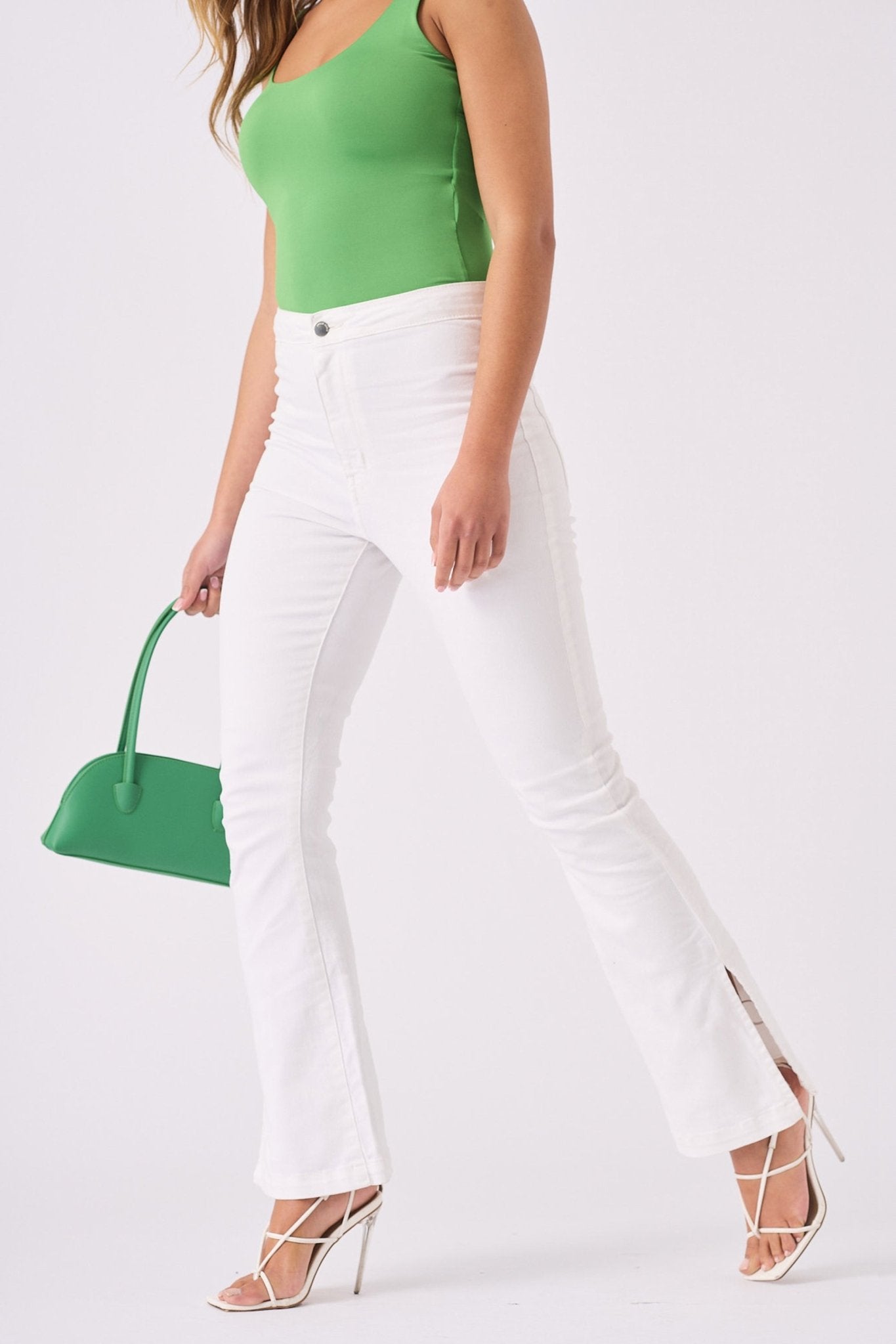 A model walking to show the movement and comfort of the white high rise bootcut jeans for women.