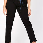 A model posing in womens high rise black frayed hem jeans featuring a stylish raw edge finish.