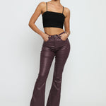 A full length shot of the maroon skinny bootcut jeans styled with black heels for a chic look.