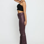 Side profile of a model wearing maroon skinny bootcut jeans highlighting the slim leg and flared hem.