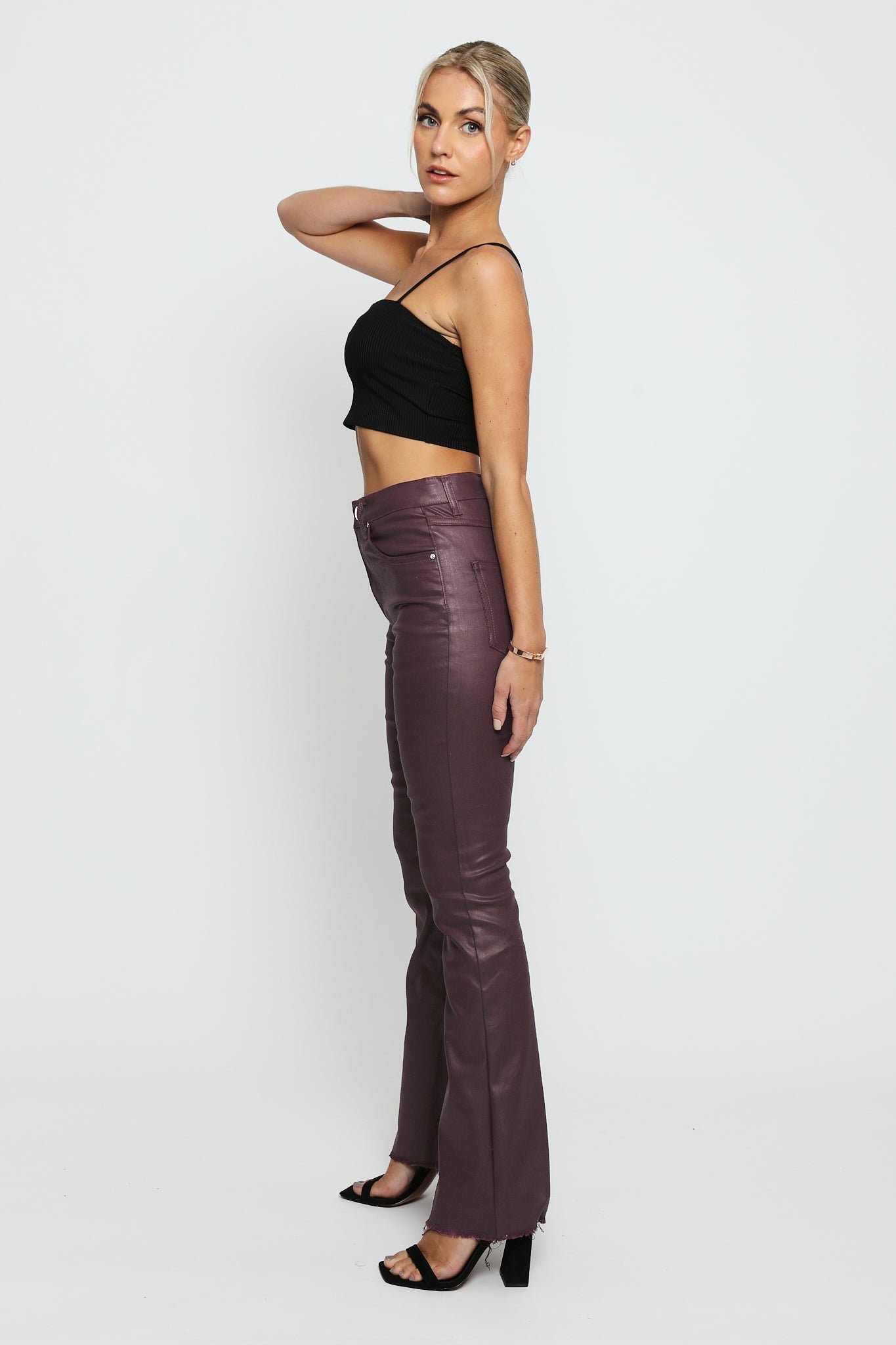 Side profile of a model wearing maroon skinny bootcut jeans highlighting the slim leg and flared hem.